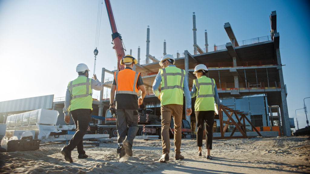 A group of commercial site development professionals walking towards a construction site.