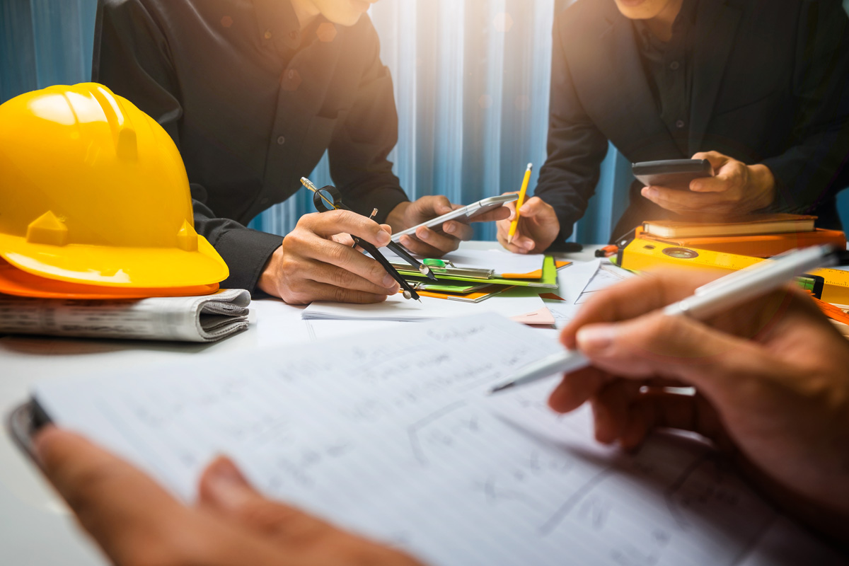 Construction managers sitting around a table with blueprints and yellow hard hats in El Paso.