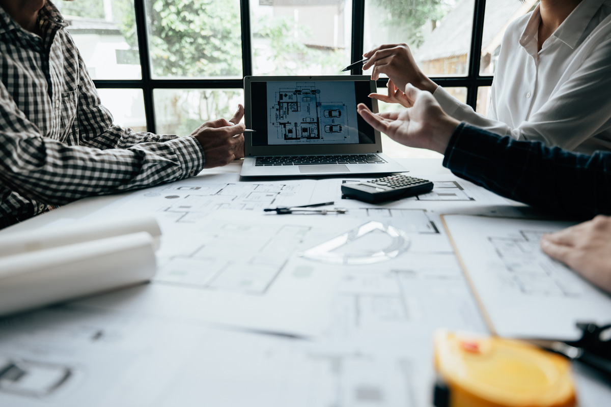 People at a desk going over blueprints on a tablet in Carlsbad. 