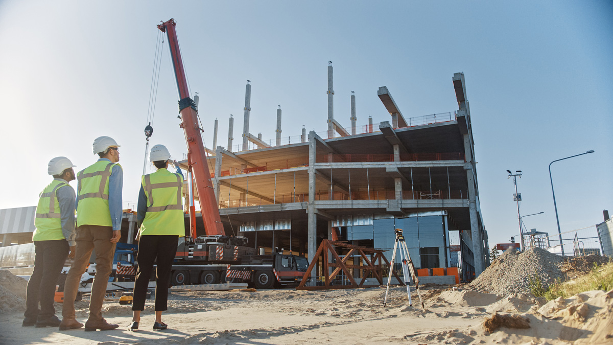 Three people looking at a commercial construction site in Carlsbad.